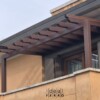 Pergotenda addossata in metallo marrone con telo teso retrattile installata su terrazzo