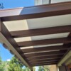 Pergotenda addossata in metallo marrone con telo teso retrattile installata su terrazzo